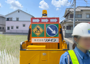 警備車両の前に立つ警備員の女性
